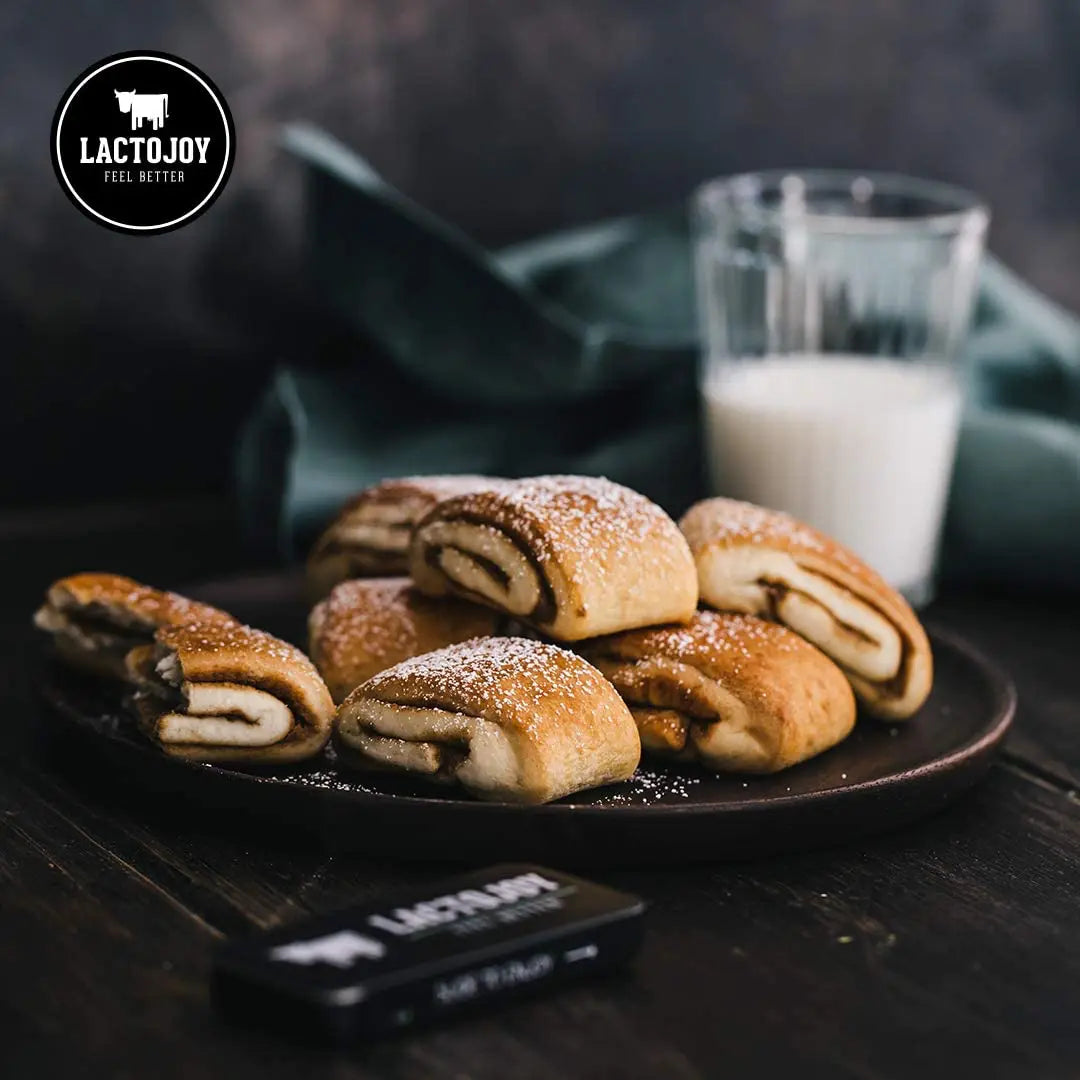Pasticcini su un piatto con un bicchiere di latte e il logo LactoJoy sullo sfondo