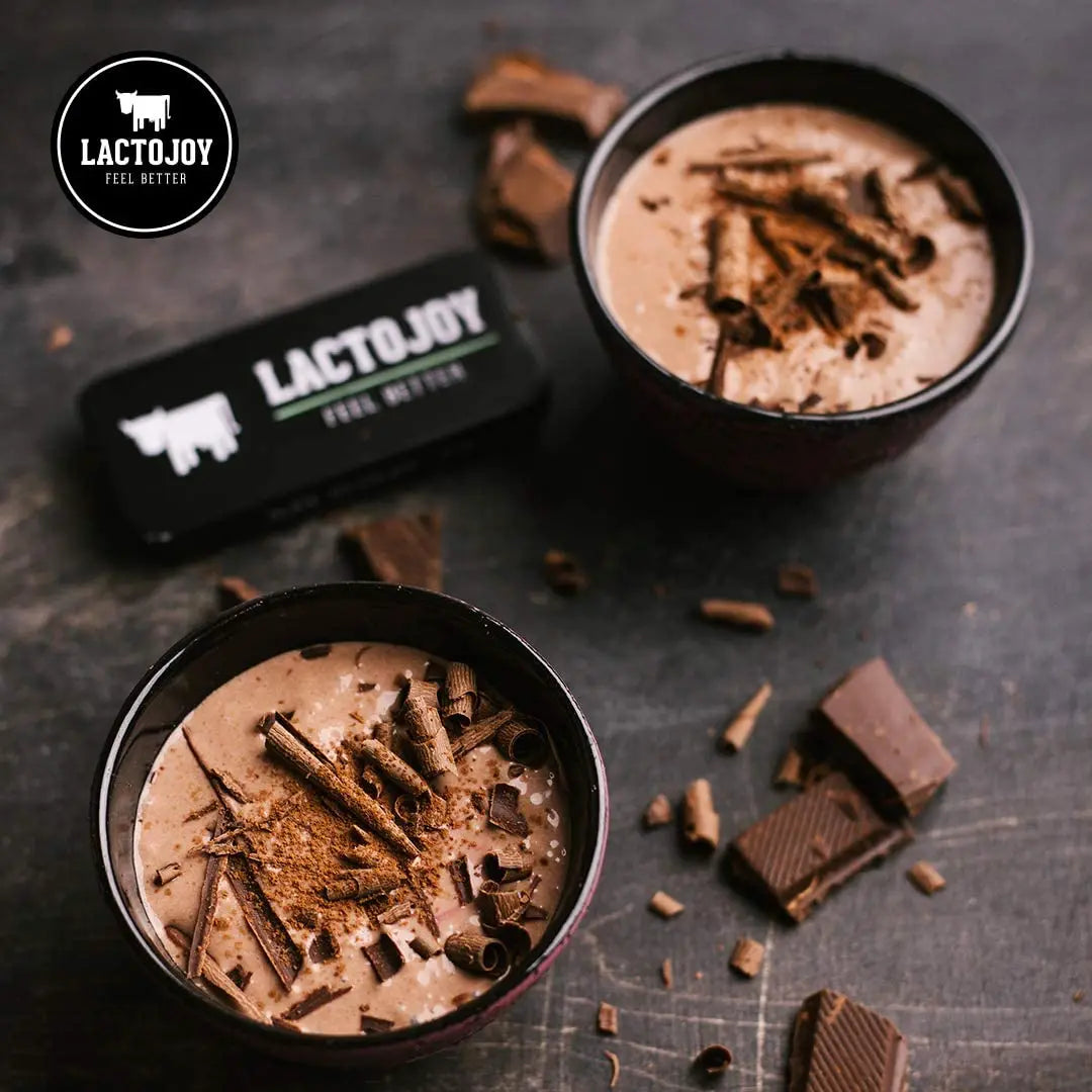 Due coppette di dessert al cioccolato con il marchio LactoJoy su una superficie scura.